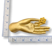 A golden mudra hand incense burner beside rulers for scale on a white background.