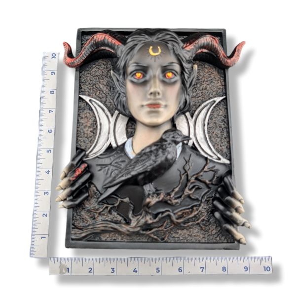 A gothic fantasy wall plaque featuring a horned woman with glowing orange eyes, black horns, white triple moons, skeletal hands, a raven, and a barren tree, shown with measurement rulers on a white background.