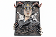 A gothic fantasy wall plaque featuring a horned female figure with glowing orange eyes, crescent moon symbols, skeletal hands, and a raven perched on her shoulder, set against a plain white background.
