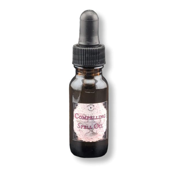 A small amber glass dropper bottle labeled 'Compelling Spell Oil' with a black rubber dropper cap, shown on a plain white background.
