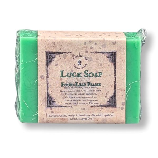 A wrapped bar of bright green soap with a paper label reading 'Luck Soap' and 'Four Leaf Flame,' photographed on a plain white background.