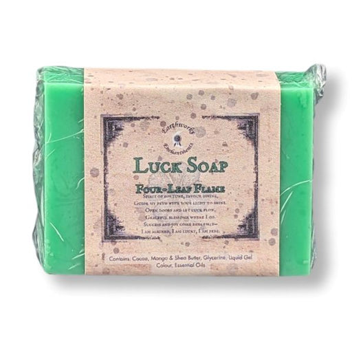 A wrapped bar of bright green soap with a paper label reading 'Luck Soap' and 'Four Leaf Flame,' photographed on a plain white background.
