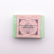 A wrapped bar of soap with a pale green outer layer and a dusty pink paper label reading 'Archanged Raphael Soap' on a plain white background.