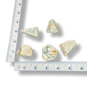Five mineral specimens on a ruler for scale on a white background