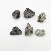 Six rough, unpolished dark gray and black stones arranged in two rows on a plain white background.
