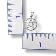 Silver pentagram pendant next to a ruler on a white background