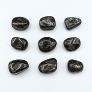 Nine polished black tumbled stones arranged in a 3x3 grid on a plain white background.