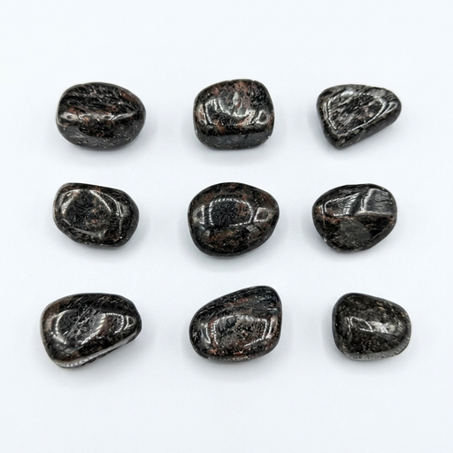 Nine polished black tumbled stones arranged in a 3x3 grid on a plain white background.