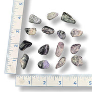 Charoite specimens with a ruler for scale on a white background