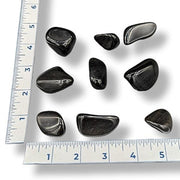 Black stones on a white surface with a ruler for scale.