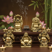 Set of gold Buddha statues with incense and candles on a wooden table with a blurred floral background.