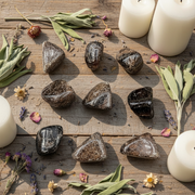 Tumbled garnet stones on a wooden table with candles, herbs 