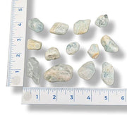 Set of rough gemstones with a ruler for scale on a white background