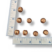 Copper spheres with a ruler for scale on a white background