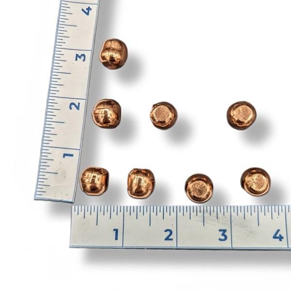 Copper spheres with a ruler for scale on a white background