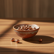 Ceramic bowl filled with copper spheres  on a wooden surface