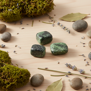 Green stones on a wooden surface with moss and leaves