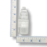 A selenite tower next to a ruler for scale on a white background