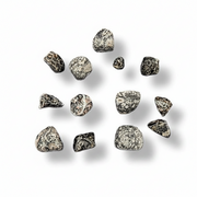 A set of small irregular polished stones  in a mottled black and white pattern, arranged on a plain white background with soft drop shadows.