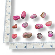 Pink and brown pebbles next to a ruler on a white background