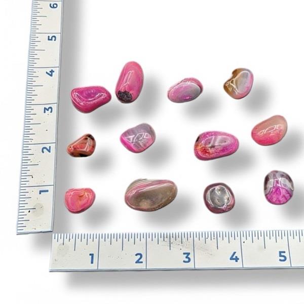 Pink and brown pebbles next to a ruler on a white background