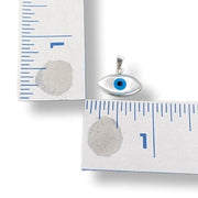 Silver eye-shaped pendant with blue stone on a white background with measurement ruler