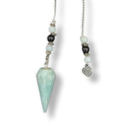 Pendulum with a green crystal and heart charm on a white background