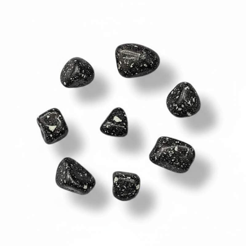 Seven small polished black tumbled stones with white speckles, arranged in a loose circle on a white background with soft drop shadows.