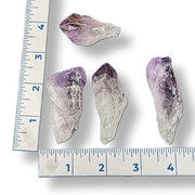 Four crystal specimens next to a ruler on a white background