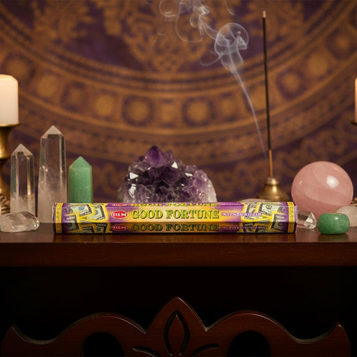 Incense stick labeled 'Good Fortune' with crystals and a candle on a decorative background