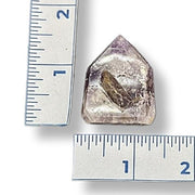 Amethyst point next to a ruler on a white background
