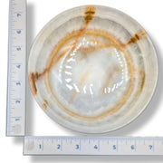 Decorative bowl with concentric circles and a ruler for scale on a white background