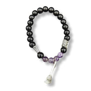 Black beaded bracelet with purple accents and a silver broom on a white background