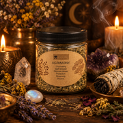 A plastic jar of Agrimony Unbinding Spell Breaker surrounded by mystical props including a smudge bundle, crystals, dried flowers, and burning candles on a rustic wooden surface.