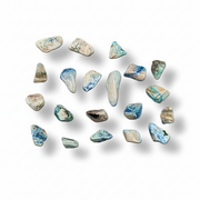 A set of polished tumbled pebble stones in shades of blue, beige, gray, and white, arranged on a clean white background with soft drop shadows.