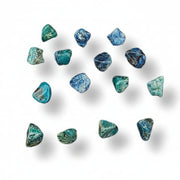 Tumbled chrysocolla stones with a ruler for scale on a white background