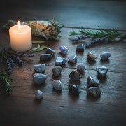tumbled tanzanite stones in a spiritual setting with lavender, sage and a lit candle.