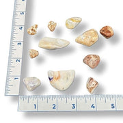 A collection of tumbled opal rocks of various sizes next to a ruler for scale, with numbers 1 to 6 visible.