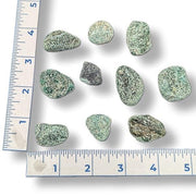 Set of greenish rocks next to a ruler on a white background