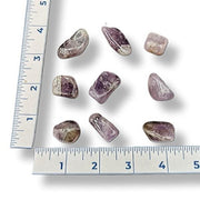 Purple gemstones with a ruler for scale on a white background