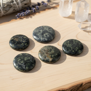Five marbled stones on a wooden surface with crystals in the background