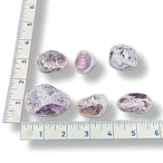 Purple gemstones with a ruler for scale on a white background