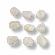 Nine smooth, polished tumbled stones in a light cream to off-pink color, arranged in a 3x3 grid on a white background with soft drop shadows.