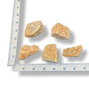 Five rocks of varying sizes on a white background with a ruler for scale.