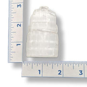 A selenite tower next to a ruler on a white background
