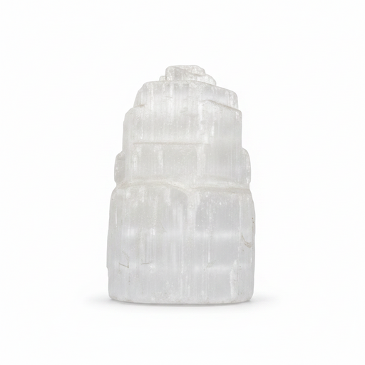 A white selenite tower figurine made of stacked, tiered selenite crystals, photographed on a seamless white background.