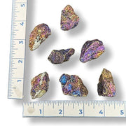 Colorful iridescent rocks on a white background with a ruler for scale.