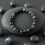 Black beaded bracelet on a dark stone with scattered beads around