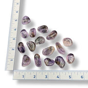 Set of purple and pink gemstones with a ruler for scale on a white background
