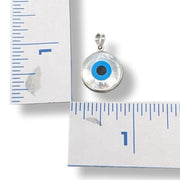 Evil eye pendant with blue center on a white background with a ruler for scale.